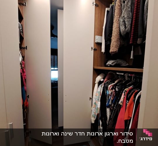 ארון בגדים פתוח עם בגדים תלויים ומדף עליון